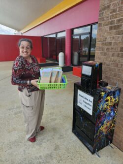 A woman holds a tray of art supplies she is preparing to put into the Little Art Supply Library