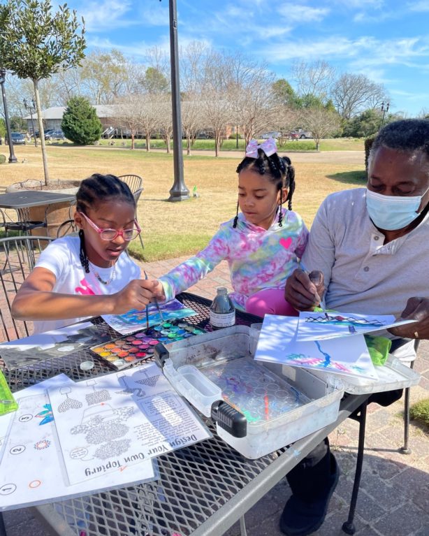 A father and his two daughters create watercolor paintings in the WMA garden.