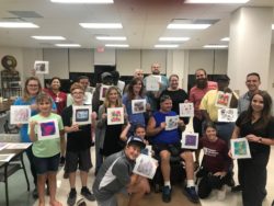 A group of people hold artwork they've just created